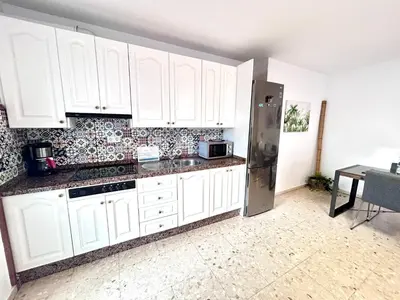 a kitchen with white cabinets and a stainless steel refrigerator at Chalet La Caballa Playa la Barrosa in Chiclana de la Frontera