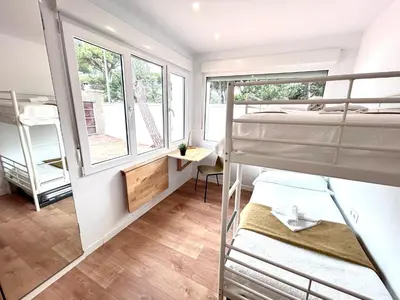 a dorm room with two bunk beds and a desk at Chalet La Caballa Playa la Barrosa in Chiclana de la Frontera