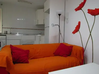 an orange couch in a kitchen with red pillows at Mi pequeño apartamento in Cádiz