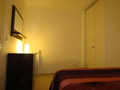 a bedroom with a bed and a dresser with a lamp at Mi pequeño apartamento in Cádiz