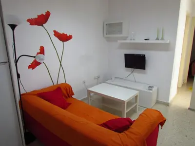 a living room with an orange couch and a table at Mi pequeño apartamento in Cádiz