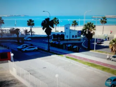 a view of a beach with palm trees and the ocean at VIVIENDA TURISTICA MARANt 2 in El Puerto de Santa María