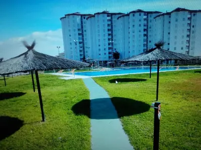 a walkway next to a swimming pool with straw umbrellas at VIVIENDA TURISTICA MARANt 2 in El Puerto de Santa María