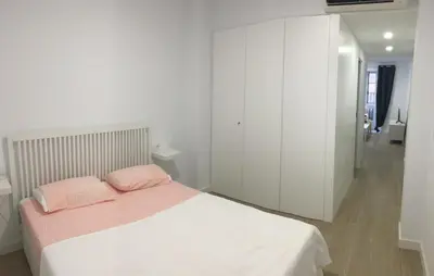 a white bedroom with a bed with two pink pillows at Alameda apodaca in Cádiz