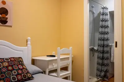 a bedroom with a bed and a table and a shower at Sanvi Xerez Centro in Jerez de la Frontera