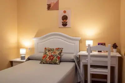 a bedroom with a white bed and a white chair at Sanvi Xerez Centro in Jerez de la Frontera