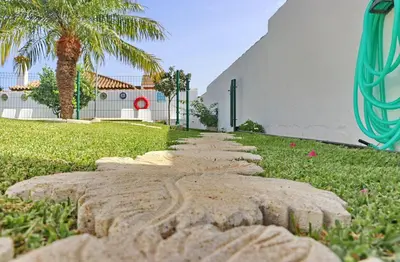 a stone path in the grass in front of a building at Bungalow Ramos in Conil de la Frontera
