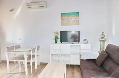 a living room with a couch and a tv and a table at Bungalow Ramos in Conil de la Frontera