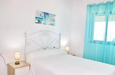 a white bedroom with a bed and a window at Bungalow Ramos in Conil de la Frontera