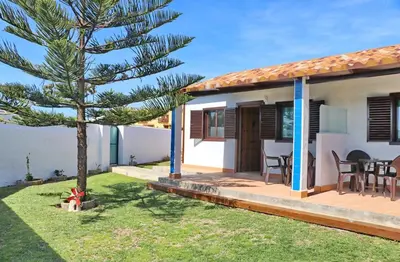 a house with a pine tree in the yard at Bungalow Ramos in Conil de la Frontera