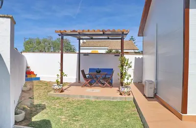a patio with a table under a pergola at Bungalow Ramos in Conil de la Frontera
