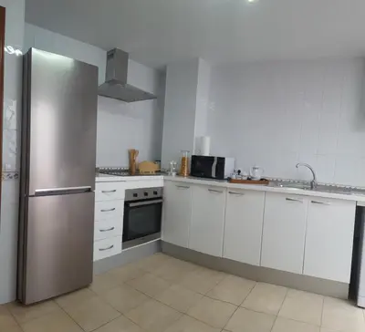 a kitchen with white cabinets and a stainless steel refrigerator at Apartamentos Coralba - Dúplex Bahía de Cádiz in San Fernando