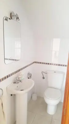 a white bathroom with a toilet and a sink at Apartamentos Coralba - Dúplex Bahía de Cádiz in San Fernando
