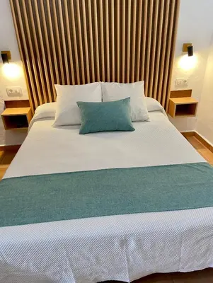 a large bed with a blue pillow on it at Apartamentos Villafaro Conil in Conil de la Frontera