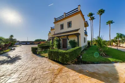 a house on a brick road with palm trees at Apartamentos Villafaro Conil in Conil de la Frontera