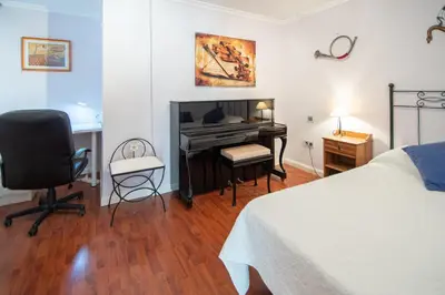 a bedroom with a bed and a desk and a piano at Apartamento El Pentagrama de Cádiz in Cádiz