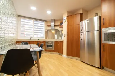a kitchen with a table and a stainless steel refrigerator at Alquileres Kakiko in Sanlúcar de Barrameda