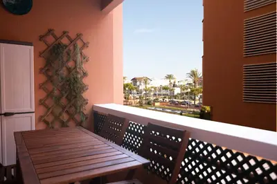 a wooden bench on a balcony with a view of the ocean at Alquileres Kakiko in Sanlúcar de Barrameda