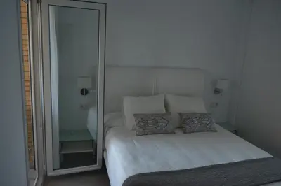 a bedroom with a bed with two pillows and a mirror at Apartamento Playa Victoria - Cádiz in Cádiz