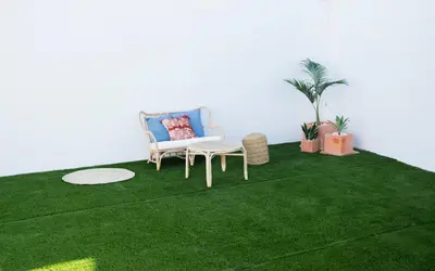 a green carpet with two chairs and a table on it at Hotel Mariantonia in Chiclana de la Frontera