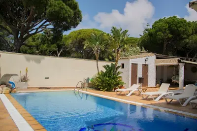 a swimming pool with lounge chairs next to a house at Hotel Mariantonia in Chiclana de la Frontera