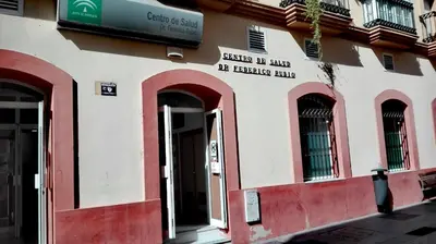 a building with red doors and windows on a street at Apartamento Santa Faz in El Puerto de Santa María