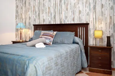 a bed with a blue comforter and two pillows at Grand Beachside Apartment - Cádiz in Cádiz