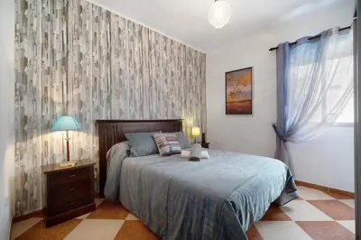 a bedroom with a bed and a dresser and a window at Grand Beachside Apartment - Cádiz in Cádiz
