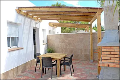 a wooden table and chairs on a patio at Bungalow La Roa V in Conil de la Frontera