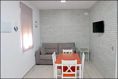 a living room with a couch and a table and chairs at Bungalow La Roa V in Conil de la Frontera