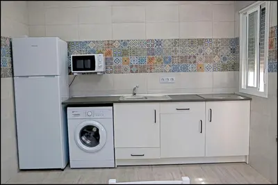 a kitchen with a white refrigerator and a washing machine at Bungalow La Roa V in Conil de la Frontera