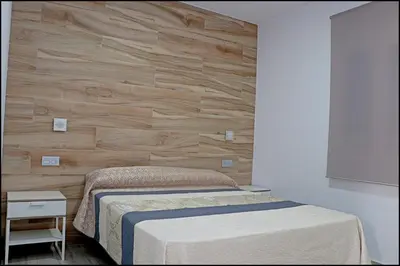 a bedroom with a bed and a wooden wall at Bungalow La Roa V in Conil de la Frontera