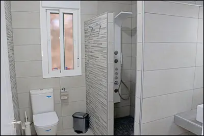 a bathroom with a shower and a toilet and a window at Bungalow La Roa V in Conil de la Frontera
