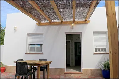 a patio with a wooden table and chairs at Bungalow La Roa V in Conil de la Frontera