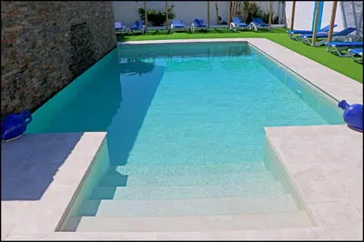 a swimming pool with blue water in a yard at Bungalow La Roa V in Conil de la Frontera