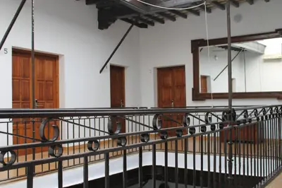 a balcony with a black railing and wooden doors at Hospederia 1881 in Chiclana de la Frontera