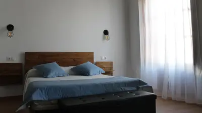 a bedroom with a bed with blue sheets and a window at Hospederia 1881 in Chiclana de la Frontera