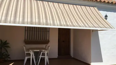 a metal roof over a table with two stools at Villa Gallardo - Cerca Playa y Pueblo in Conil de la Frontera