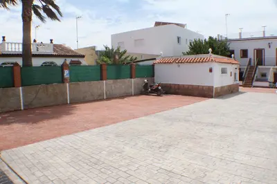 a brick courtyard with a fence and a building at Apartamentos La Palmera in Conil de la Frontera