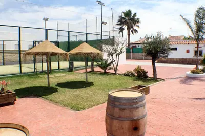 a patio with a barrel and straw umbrellas at Apartamentos La Palmera in Conil de la Frontera