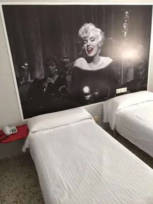 a poster of a woman on a wall in a room with two beds at Hotel Sur Utopia in El Puerto de Santa María