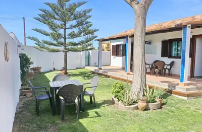 a garden with a table and chairs and a tree at Bungalow Ramos II in Conil de la Frontera