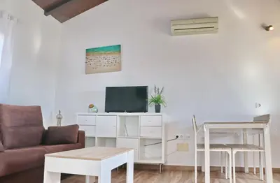 a living room with a couch and a tv at Bungalow Ramos II in Conil de la Frontera