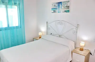 a white bedroom with a white bed and a window at Bungalow Ramos II in Conil de la Frontera