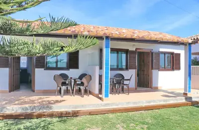 a house with a table and chairs on a deck at Bungalow Ramos II in Conil de la Frontera