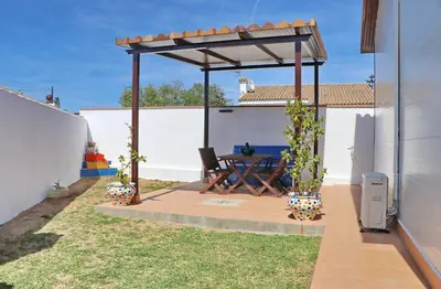 a patio with a wooden table under a pergola at Bungalow Ramos II in Conil de la Frontera
