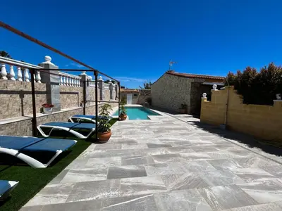 a patio with two lounge chairs and a swimming pool at Villa Rosal- Solo familias y parejas in Conil de la Frontera
