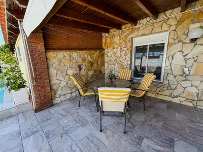 a patio with a table and chairs and a stone wall at Villa Rosal- Solo familias y parejas in Conil de la Frontera