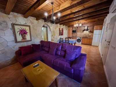 a living room with a purple couch and a kitchen at Villa Rosal- Solo familias y parejas in Conil de la Frontera
