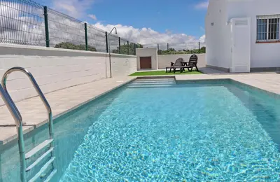 a swimming pool with blue water in front of a house at Chalet Lobita in Conil de la Frontera